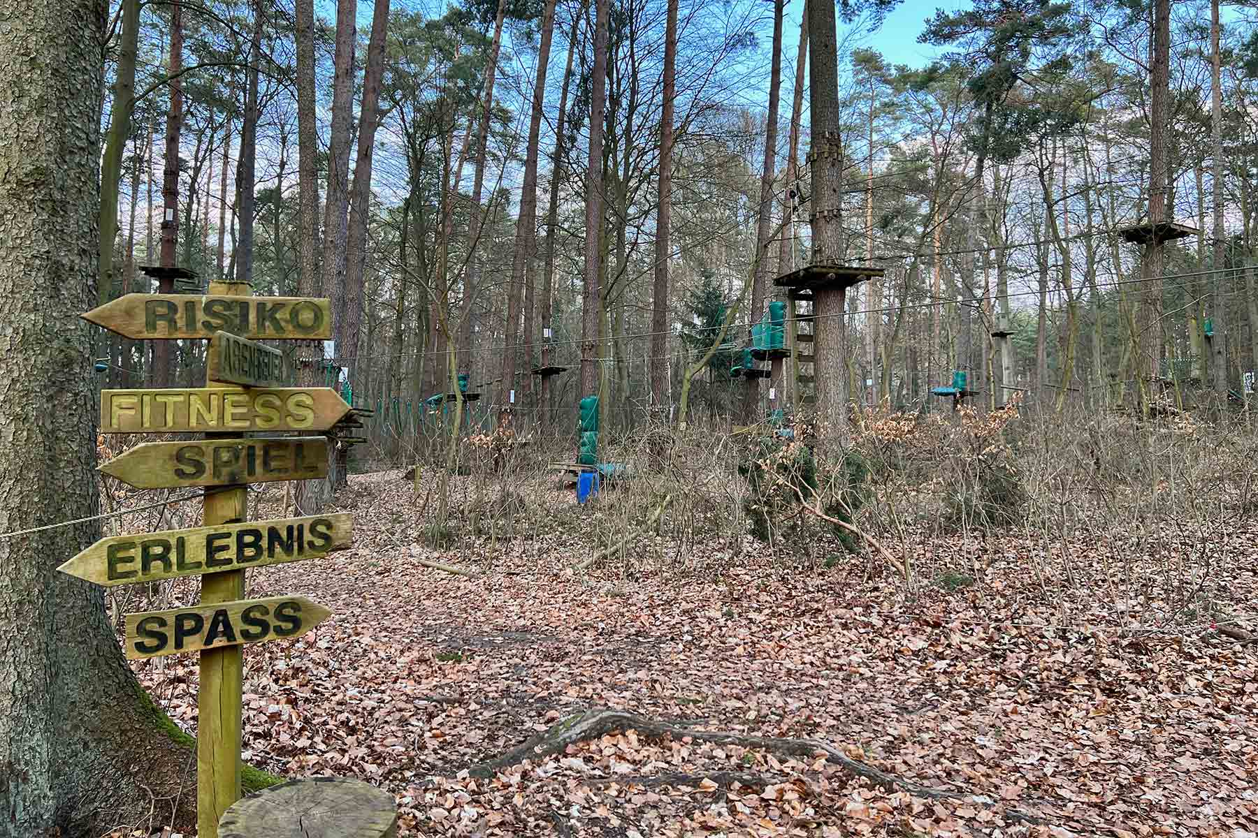 Kletterstationen in verschiedenen Höhen im Kletterwald Usedom mit Wegweiser